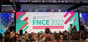 Auditorium with FNCE 2022 banner and people taking their seats